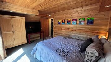 Ein Schlafzimmer mit Holzwänden, einem Bett, einem Fernseher und einem an der Wand befestigten Kunstwerk.