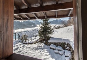 A snow-covered landscape with a wooden structure, a small tree, and a stone wall.