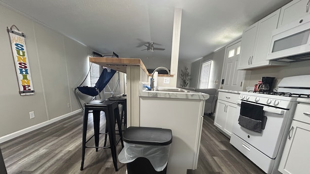 A compact kitchen with a central island, a stove, and a ceiling fan.
