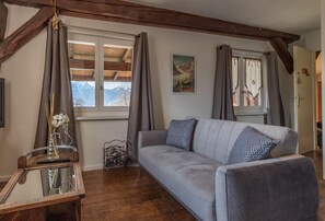 Una sala de estar con un sofá, una mesa de centro de vidrio, un jarrón con flores y un cartel en la pared.