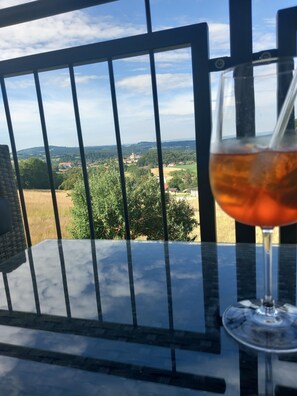 A glass of red wine on a table with a view of a rural landscape through a metal railing. - Traumhaftes neu Renoviertes Apartment mit Herrlichem Ausblick & top Ausstattung (Lalling)
