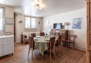 Un coin repas comprenant une table ronde, des chaises, un canapé, un téléviseur et une affiche accrochée au mur.