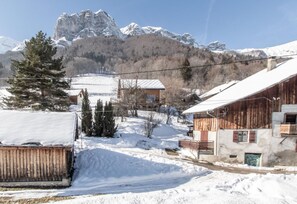 A snow-covered village with rustic buildings, a wooden barn, and a mountain backdrop.