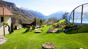 A residential property with a well-maintained lawn, a swimming pool, and a view of snow-capped mountains. - Apartment 'L'Ancolie' with Mountain View, Shared Terrace and Wi-Fi (Saint-Ferréol)