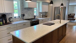 A modern kitchen with white cabinetry, a large island, stainless steel appliances, and pendant lighting. - Short Walk to the Big House, Modern Spacious 3 BR + Basement Suite, 3.5 baths (Ann Arbor)