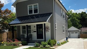 A two-story house with a covered porch, a garage, and a well-maintained lawn. - Short Walk to the Big House, Modern Spacious 3 BR + Basement Suite, 3.5 baths (Ann Arbor)