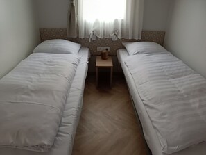 A twin room with two single beds, a small bedside table, and a window with sheer curtains. - Tidy Chalet With Dishwasher, 9 km From Maastricht (Berg en Terblijt)