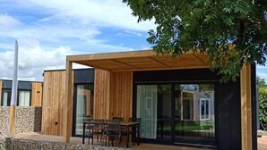 A modern outdoor seating area with a wooden pergola, stone steps, and a glass door leading to a covered patio. - Tidy Chalet With Dishwasher, 9 km From Maastricht (Berg en Terblijt)