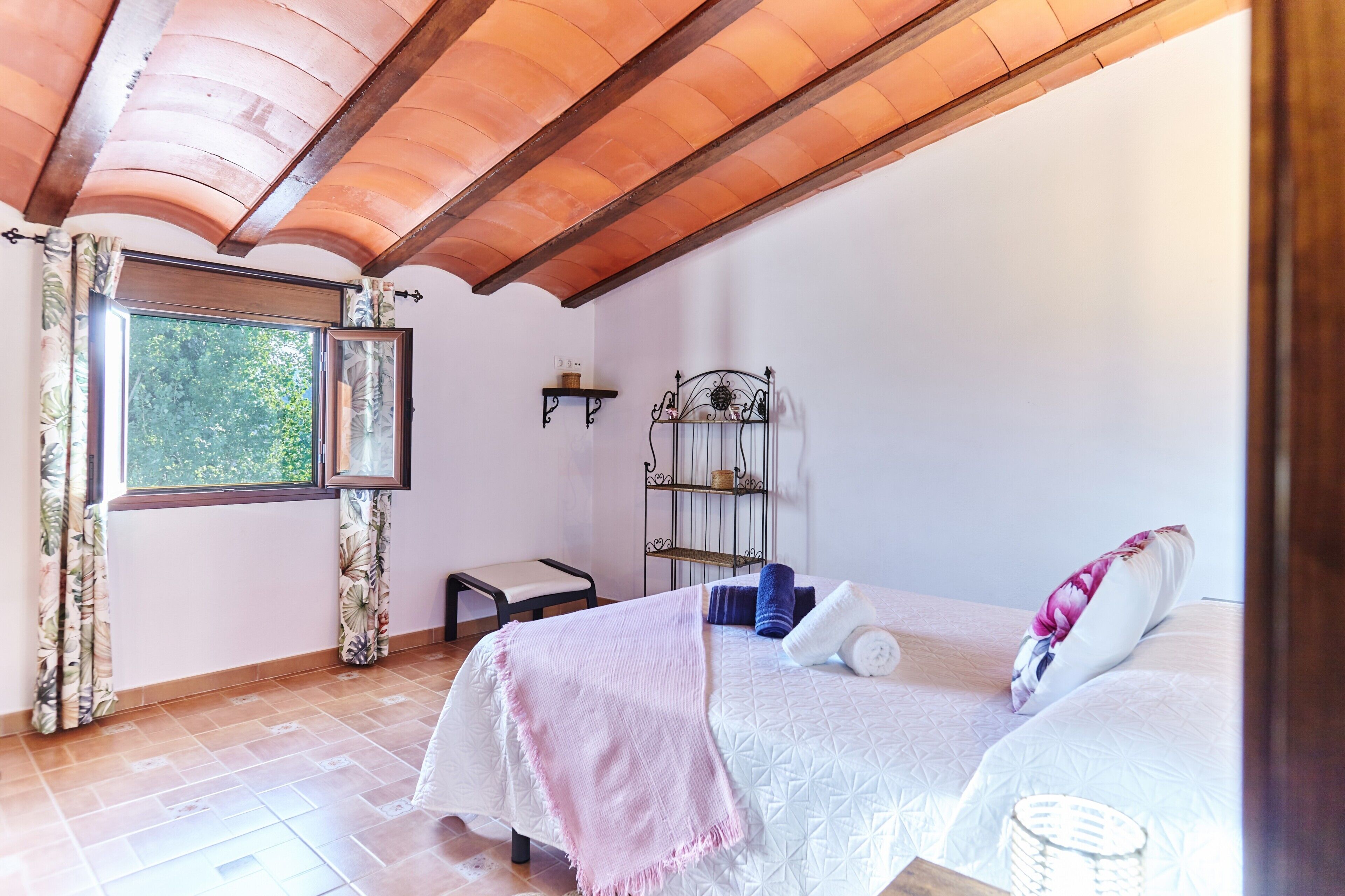 Un dormitorio con dos camas, una ventana con cortinas, un estante y una silla.
