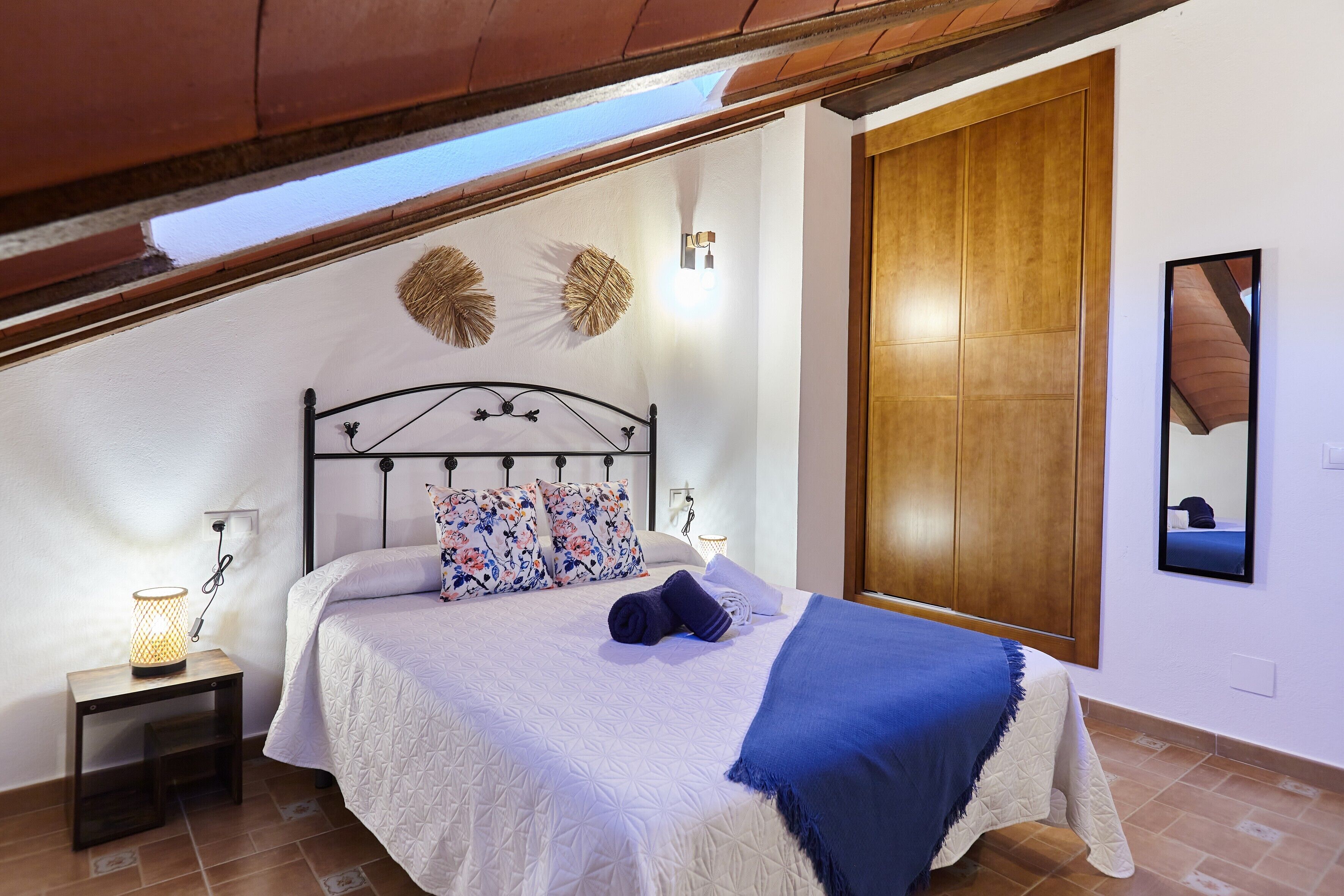 Un dormitorio con cama, mesita de noche, luz empotrada en la pared y armario de madera.