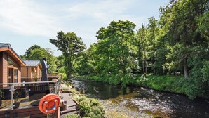 A riverside cabin with a deck overlooking a river, surrounded by lush greenery. - 3 bedroom accommodation in Dollar (Dollar)