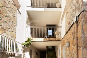 A multi-story building with balconies, stone walls, and a staircase. - 'Senya Salvi' Apartment with Sea Views, Wi-Fi, and Air Conditioning (Sant Feliu de Guíxols)