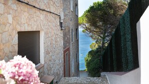 A stone building with a view of the sea, a narrow stone pathway, and a small door.