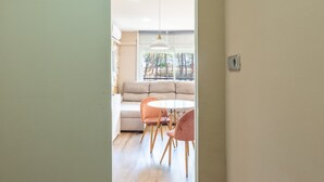 A modern interior with a sofa, round table, and chairs, a hanging light fixture, and a window with a view.