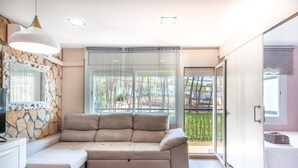 A modern room with a sectional sofa, a stone accent wall, a large window with a view, and a sliding door leading to an outdoor area.