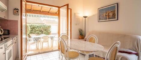 Un coin repas avec une table ronde et des chaises, un canapé, une plante en pot et un tableau accroché au mur.