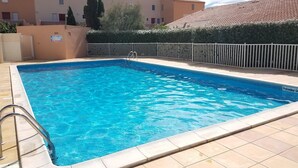 Ein rechteckiger Swimmingpool mit klarem, blauem Wasser, umgeben von einer gefliesten Liegefläche und einem weißen Zaun.