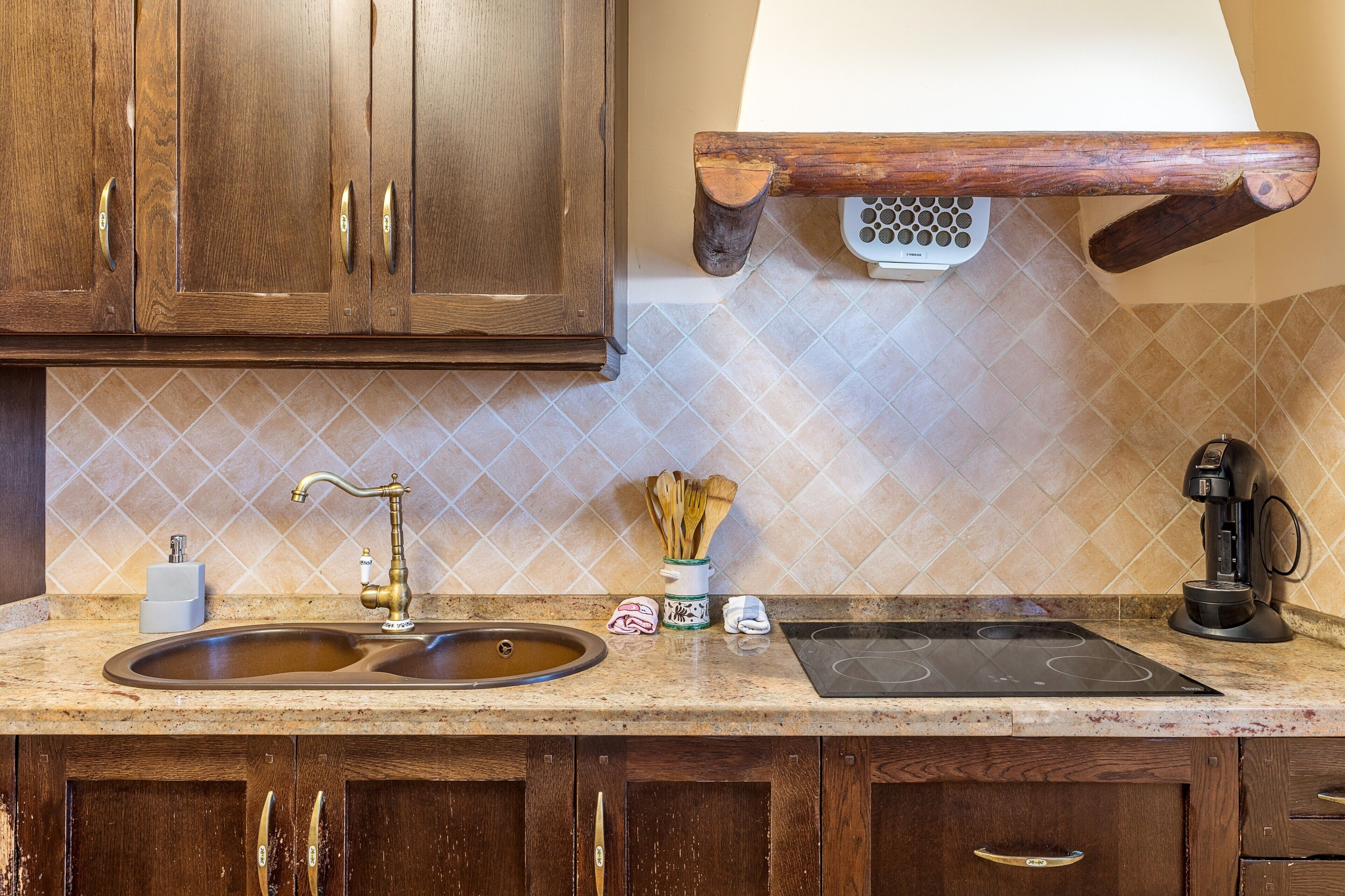 A kitchen with wooden cabinets, a double sink, a coffee maker, and a stove.