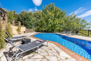 A swimming pool with lounge chairs and a stone patio.