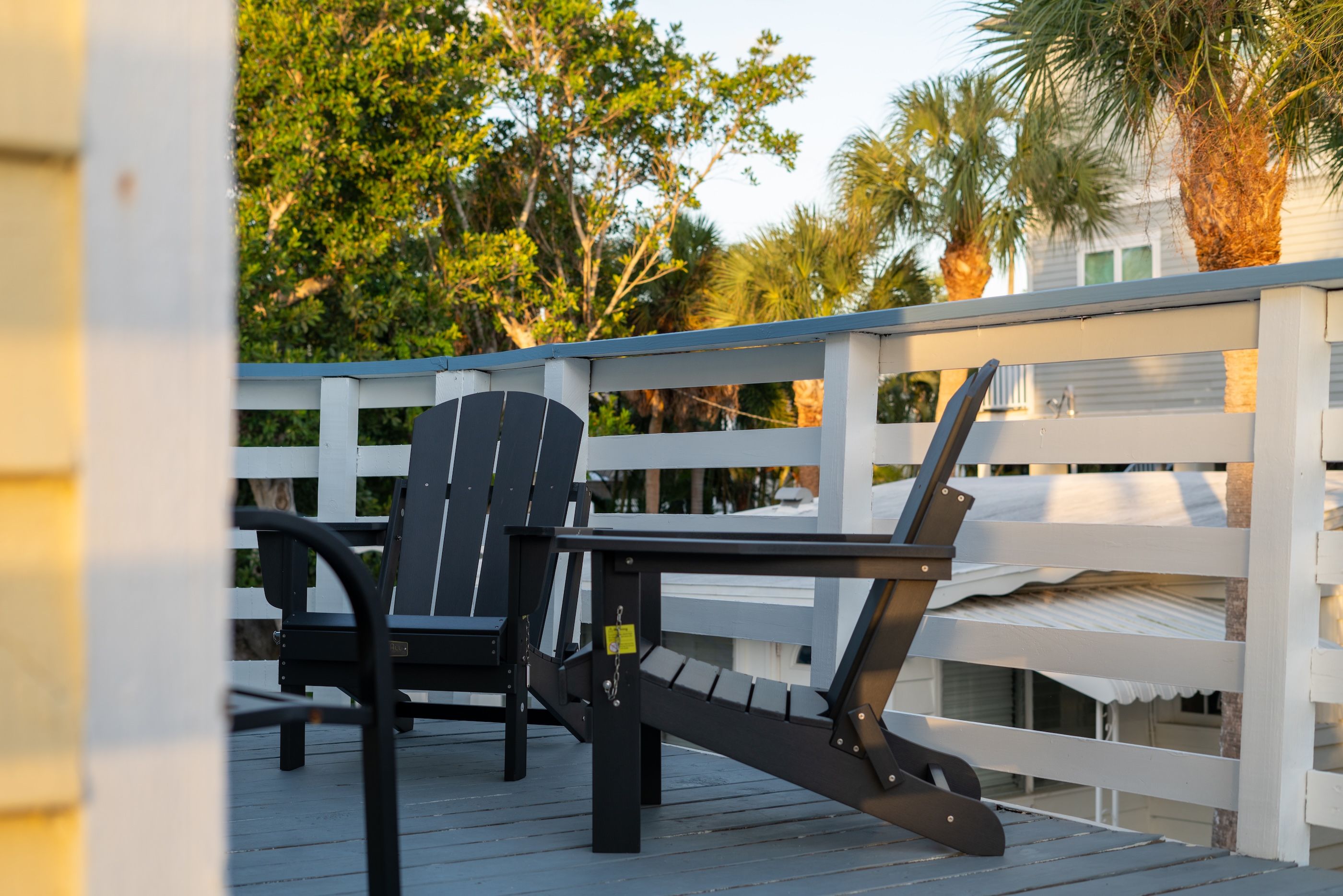 A deck with a white railing, a black chair, and a black table.