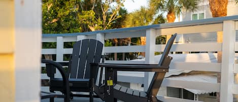 A deck with a white railing, a black chair, and a black table.