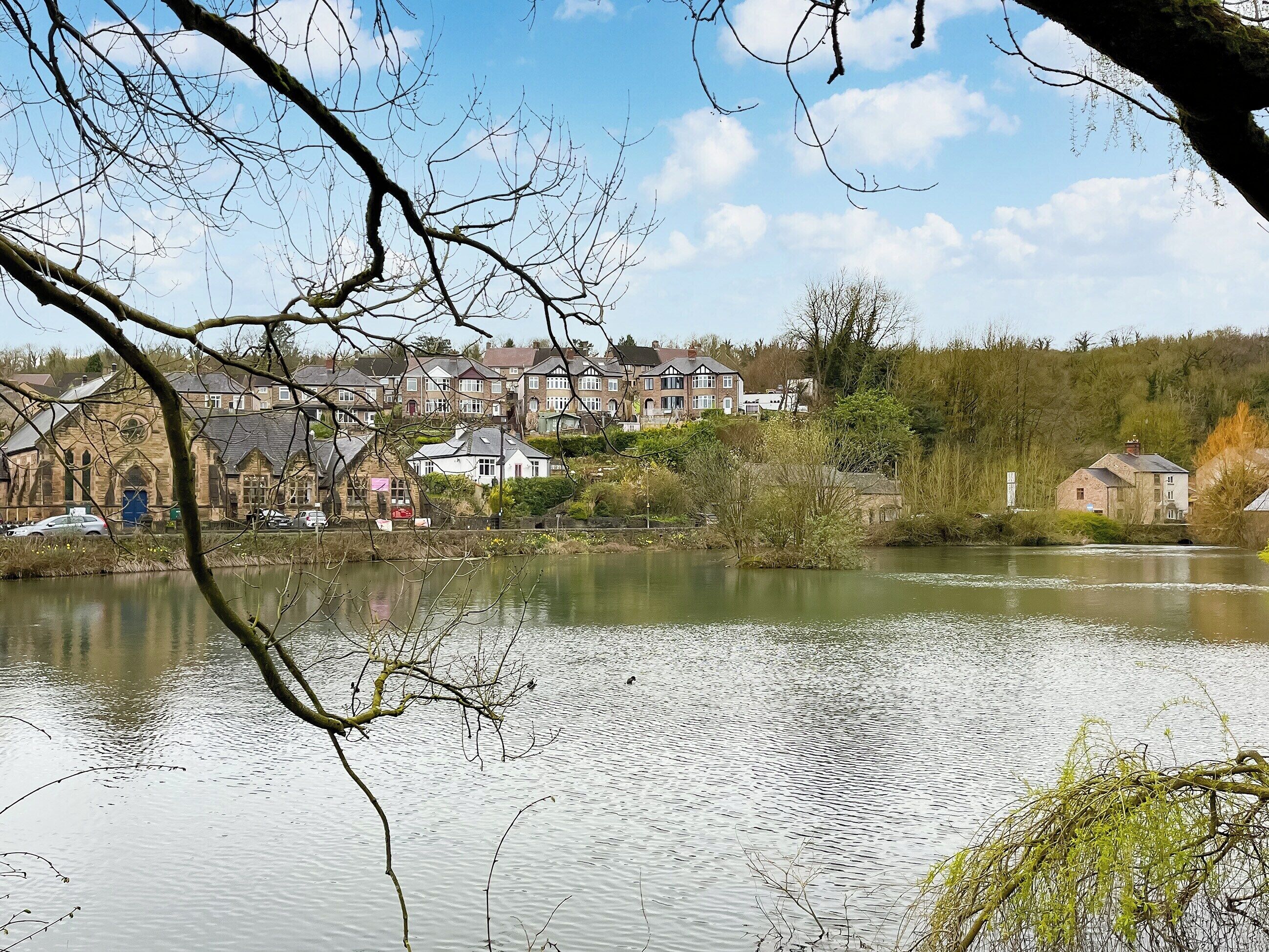 A riverside view with houses, a church, and a bridge.