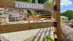 Un cancello di legno con un cartello che riporta la scritta 'ROSE COTTAGE'.