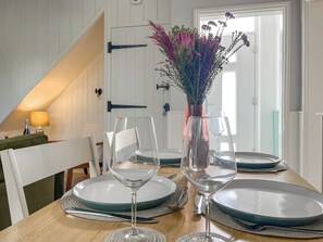 Ett matbord dukat med tallrikar, glas och en vas med blommor.