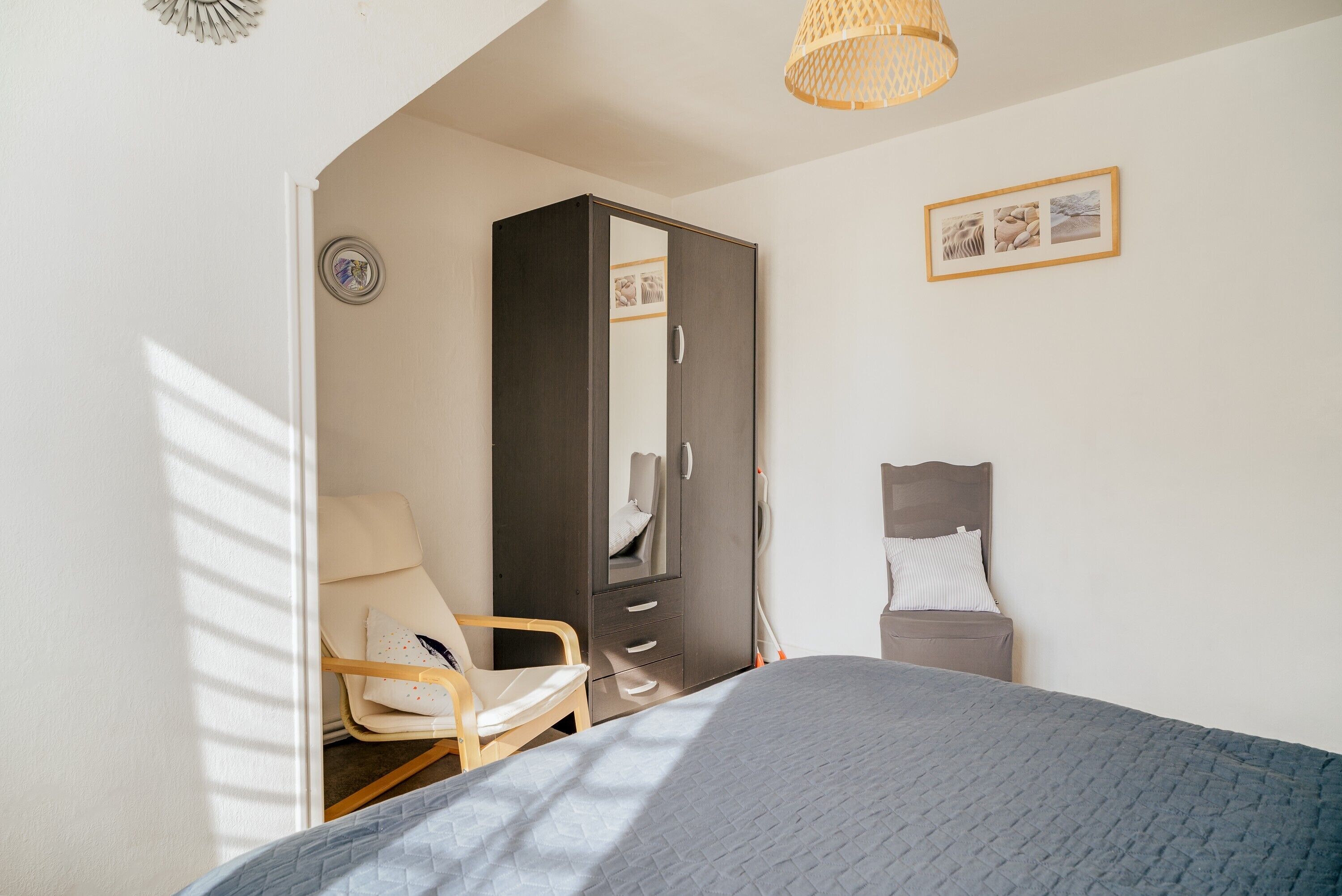 Ein Schlafzimmer mit Bett, Stuhl, Kleiderschrank, Nachttisch und Pendelleuchte.