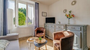 A room with a sofa, two leather chairs, a TV, a cabinet, and a window with curtains. - Holiday Home 'Maison Chaleureuse Cancale' with Private Terrace and Garden (Cancale)