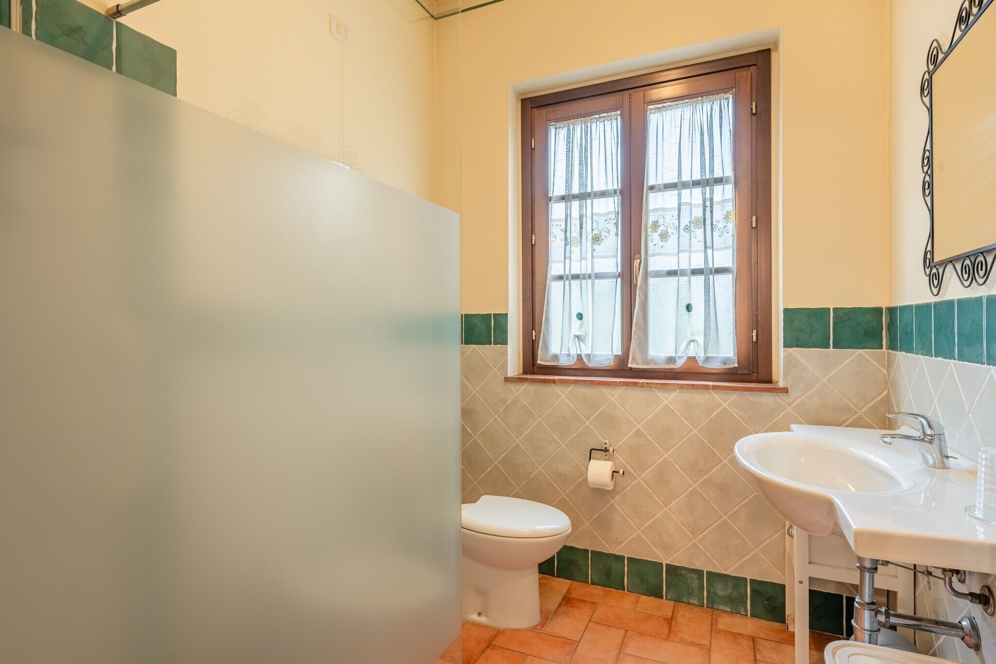 Een badkamer met toilet, wastafel en raam.