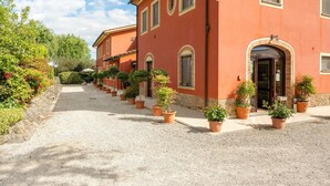 Un bâtiment avec un chemin de gravier bordé de plantes en pot, une façade rouge et un ciel dégagé.