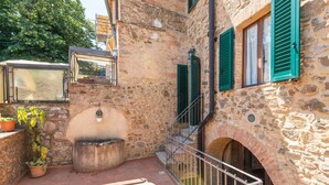 A stone courtyard with a small fountain, a metal railing, and a staircase leading to an upper level. - Room 'Camera Verde' with Shared Terrace and Wi-Fi (Montalcino)