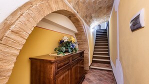 A hallway with a wooden cabinet, a flower arrangement, and a staircase. - Room 'Camera Verde' with Shared Terrace and Wi-Fi (Montalcino)