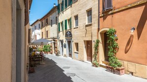 A narrow street with buildings, outdoor seating, and potted plants. - Room 'Camera Verde' with Shared Terrace and Wi-Fi (Montalcino)