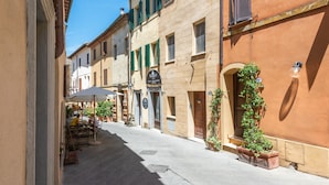 A narrow street with buildings, outdoor seating, and potted plants. - Room 'Camera Rossa' with Shared Terrace and Wi-Fi (Montalcino)