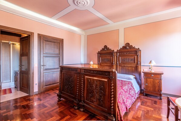 A bedroom with a wooden bed, a nightstand, and a door leading to another room.