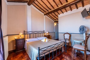 Un dormitorio con estructura de cama metálica, lámparas de noche, una mesita pequeña y una silla.