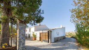 A building with a stone sign reading 'CORTIJO EL ALAMO' and a white exterior with a wooden door and a metal gate.