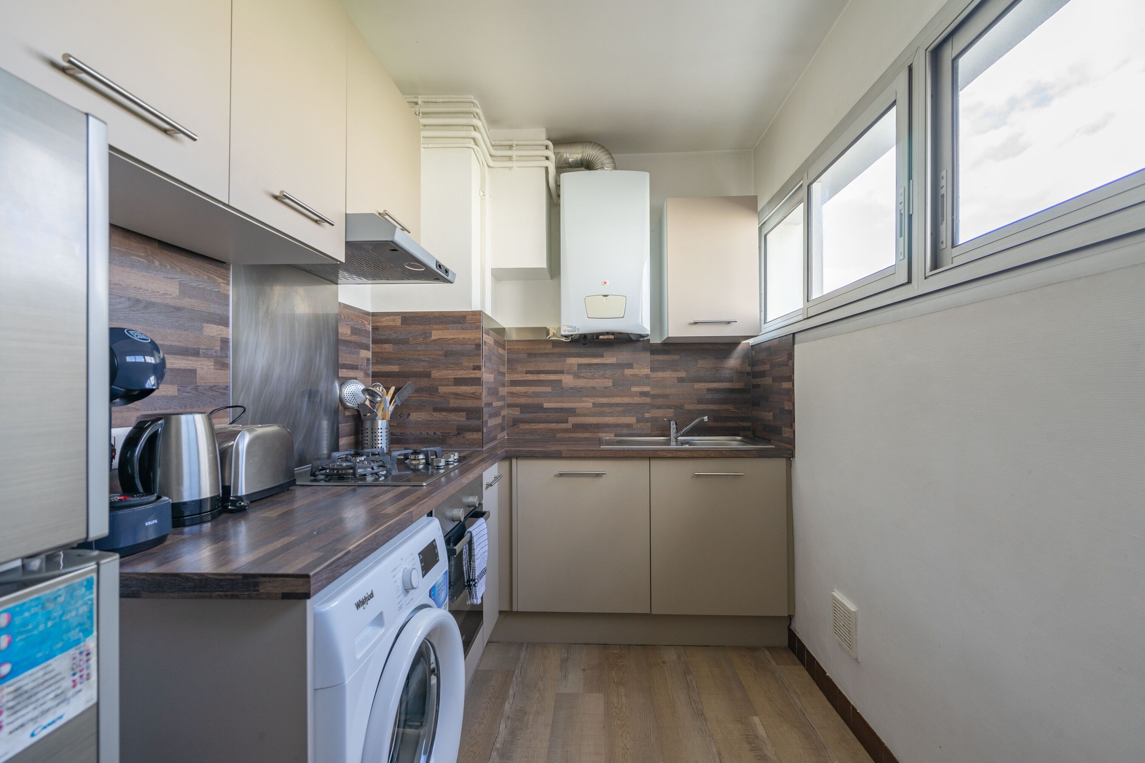 Een kleine keuken met een wasmachine, een koffiezetapparaat en een broodrooster.