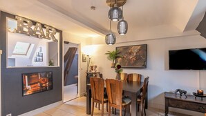 Een moderne eetruimte met een barbord, een grote flatscreen-tv en een eettafel met stoelen.