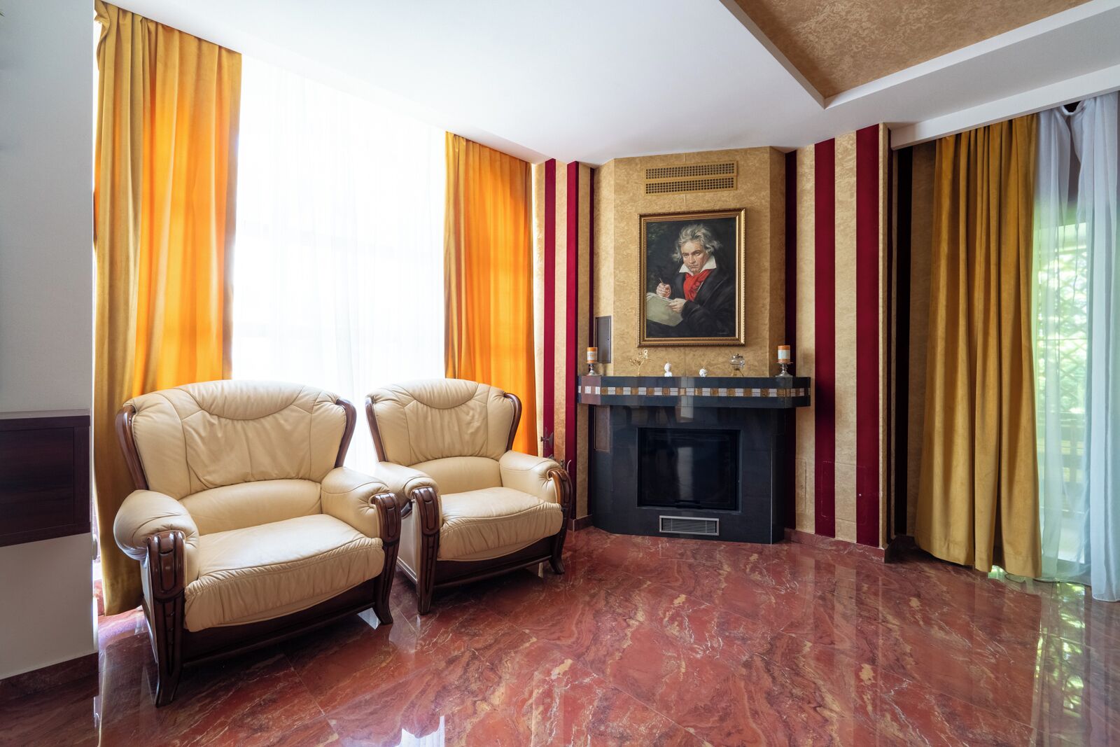 A room with two leather armchairs, a fireplace, and a painting on the wall.