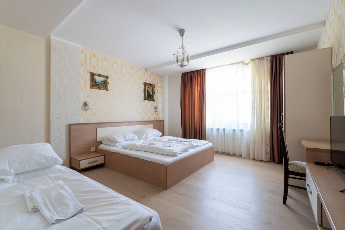 Habitación de hotel con una cama grande, un escritorio y un televisor.