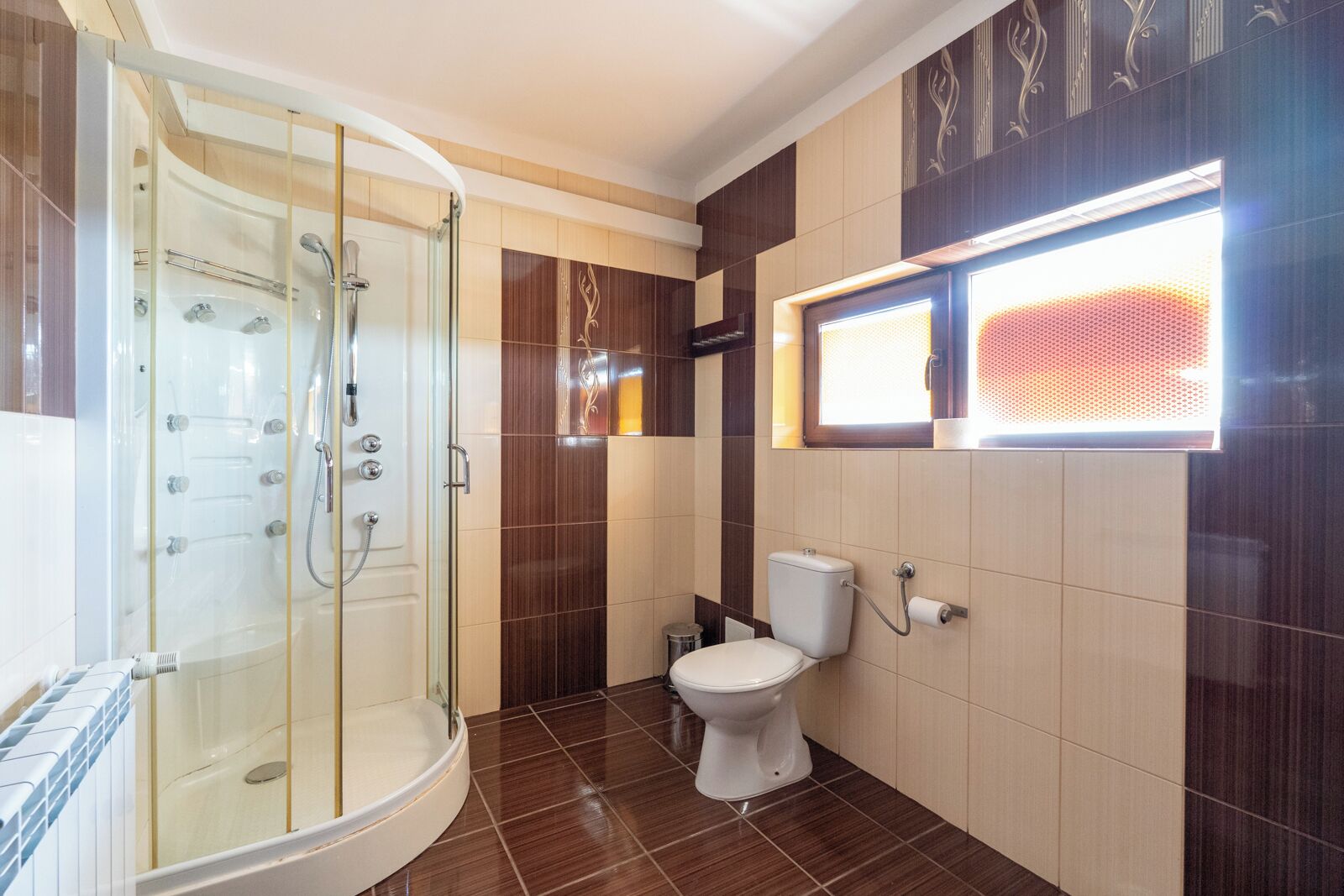 A modern bathroom with a glass-enclosed shower, a toilet, and a vanity with a mirror.