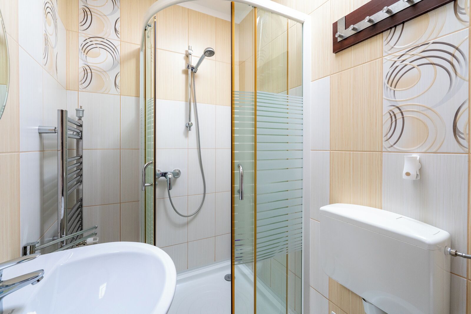 Un baño moderno con cabina de ducha de vidrio, un lavabo blanco y un inodoro.