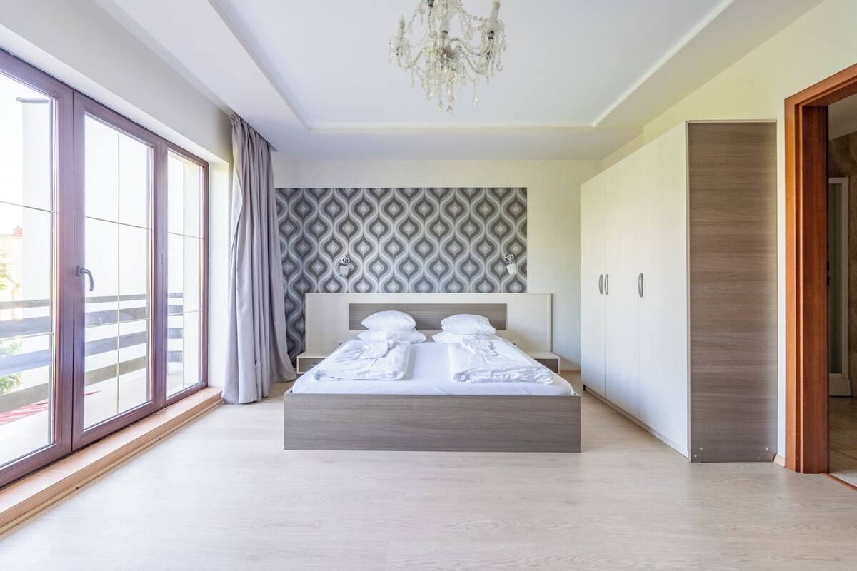Un dormitorio moderno con una cama grande, una araña y un papel tapiz estampado.