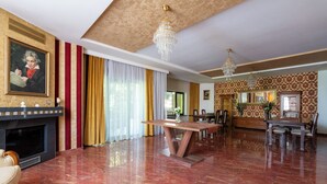 Ein großzügiges Wohnzimmer mit Kamin, einer Essecke mit Holztisch und Stühlen sowie einer Wand mit dekorativer Tapete.