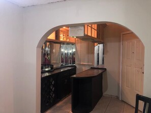 Une cuisine compacte avec un plan de travail foncé, un meuble à vin intégré et un petit îlot central.
