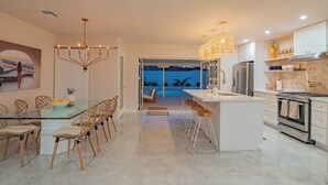 Una cocina moderna con una isla central, taburetes de bar y vistas a una piscina.