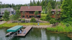 A lakeside cabin with a dock, outdoor seating, and a stone retaining wall.